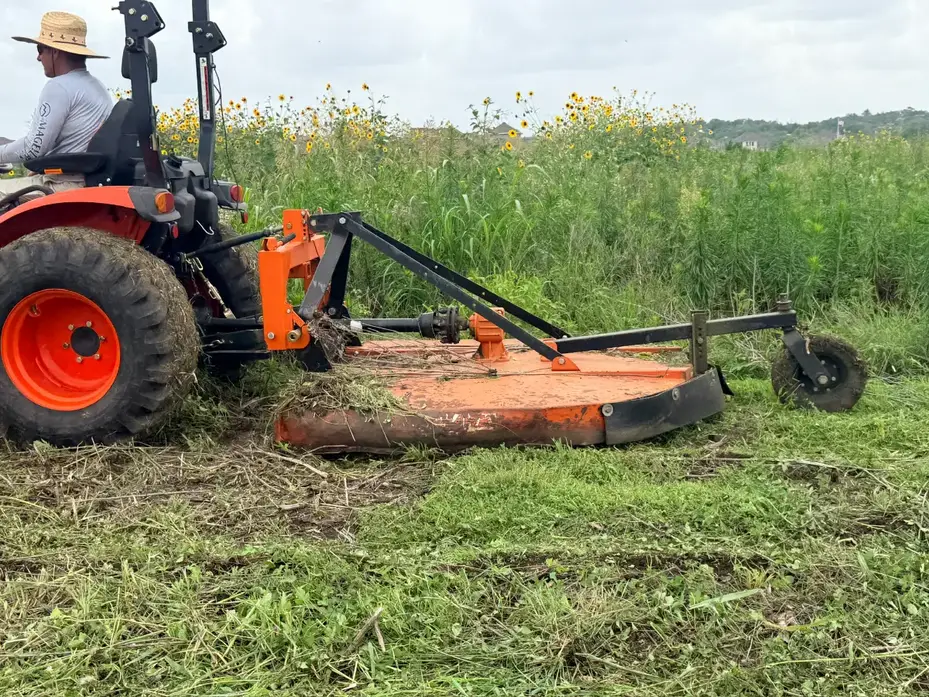 Tractor and rotary cutter shredding tall grass in Hutto TX
